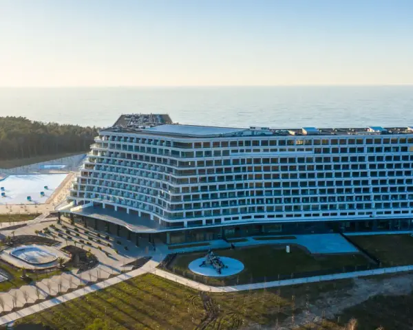 Nowoczesny, falisty pobierowo nowy hotel z basenami i widokiem na morze, otoczony lasem.