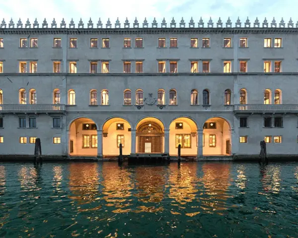 Palazzo Tedeschi a Venezia, con le sue arcate illuminate e il riflesso sull'acqua, evoca un'atmosfera magica.