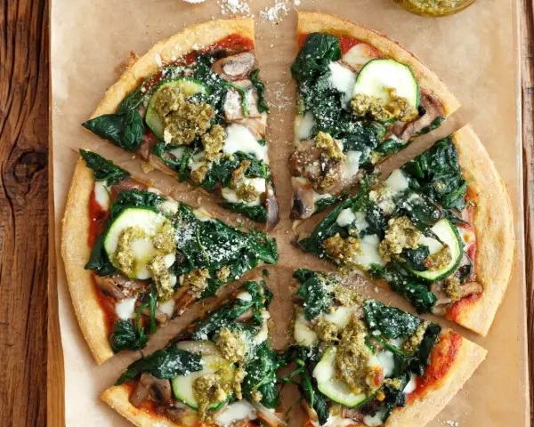 Pyszna pizza ze szpinakiem, cukinią i pieczarkami, polana zielonym pesto. Idealna na lekki obiad.