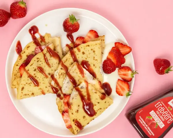 Zarte crepes ohne zucker, garniert mit frischen Erdbeeren und Erdbeer-Topping. Ein Genuss für alle, die es süß, aber zuckerarm mögen.