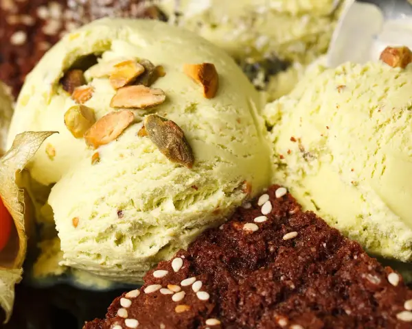 Veganes Eis selber machen: Cremiges Pistazieneis mit Nüssen und Schokostückchen, garniert mit Physalis.