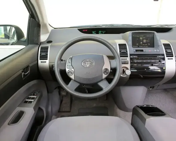 Wnętrze Toyoty Prius 2 z kierownicą, panelem radia i ekranem.