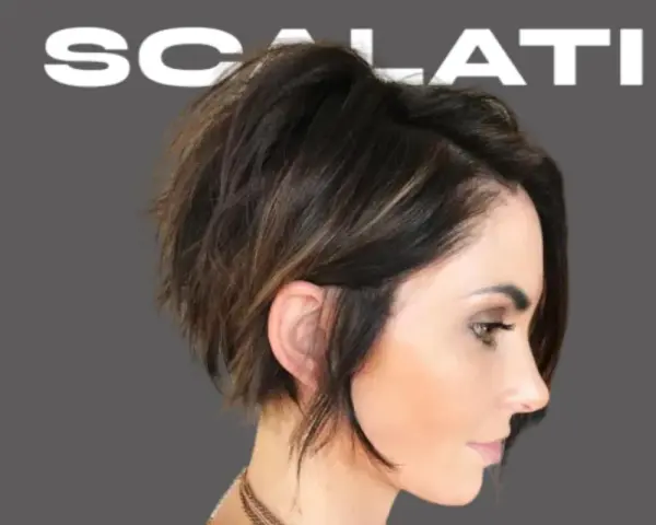 Modello con un audace taglio scalato medio corto, che incornicia il viso con ciocche texturizzate e un tocco di balayage.