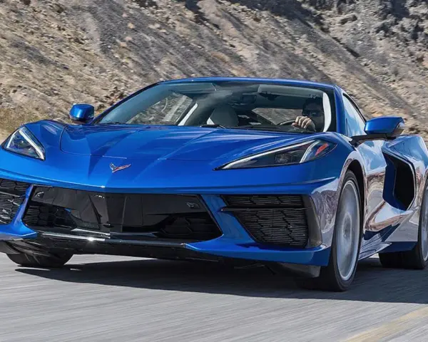 Błękitny Chevrolet Corvette Stingray pędzi po pustynnej drodze.