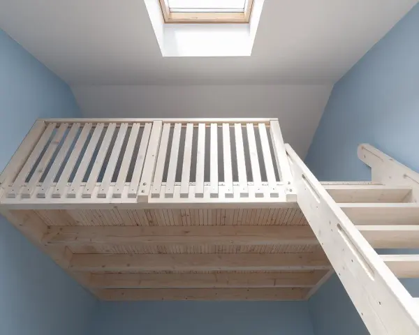 Jasna, drewniana antresola z balustradą i schodami, podświetlona przez okno dachowe.