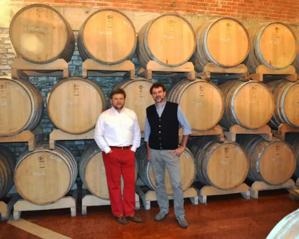 Due uomini in una cantina con botti di legno, simbolo delle migliori cantine dei Colli Euganei.