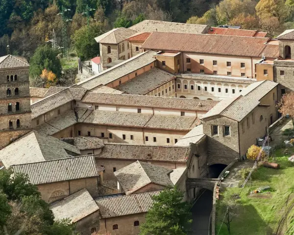 Aerial view of a sprawling monastery complex near Rome, with terracotta roofs and a tall bell tower.