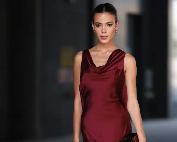 Una mujer elegante con un vestido burdeos satinado, ideal para saber como combinar un vestido burdeos para una boda.