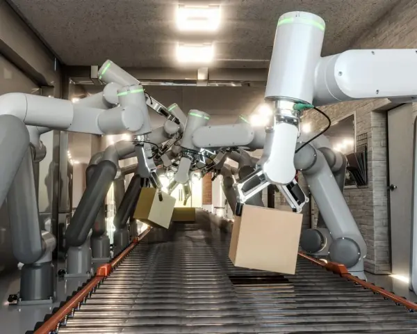 Wiele ramion robotów współpracujących chwyta kartony na linii produkcyjnej.