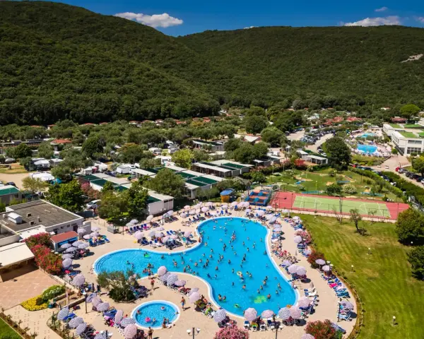 Wakacje na **camping Oliva** to baseny, korty tenisowe i mnóstwo zieleni pod górą.