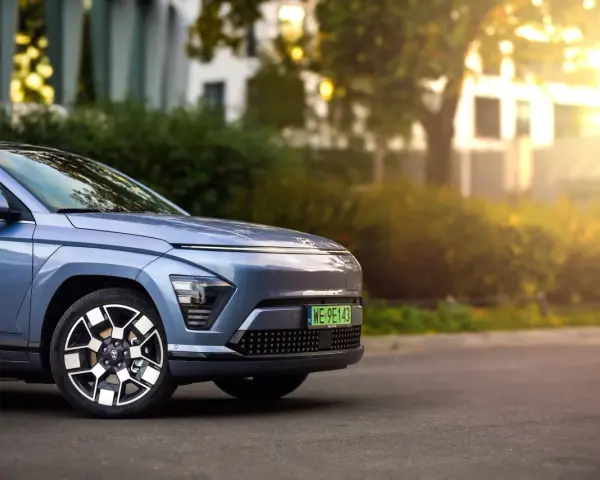 Niebieski Hyundai Kona Electric zaparkowany na ulicy, z widocznym przodem i kołem.