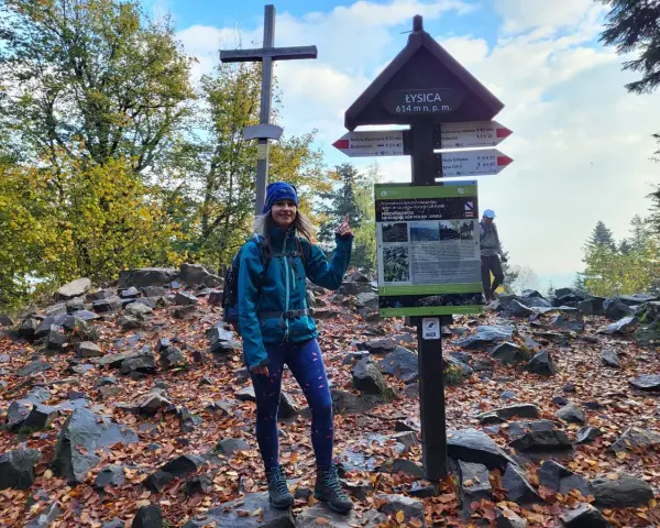 Kobieta na szczycie Łysicy, 614 m n.p.m., z drogowskazem. Jesienny szlak na Łysicę wita turystów.