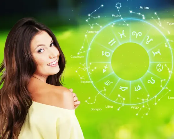 Uśmiechnięta kobieta na tle koła zodiaku. Sprawdź swój horoskop dzienny rak i odkryj, co przyniesie Ci dzień.