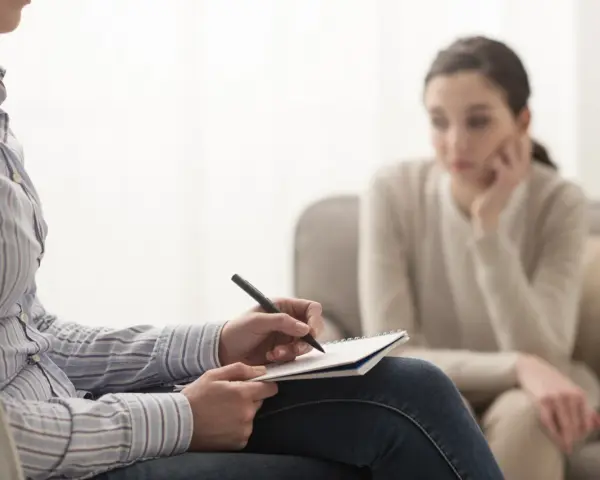 Psycholog notuje, analizując sytuację pacjentki. Zarobki psychologa zależą od doświadczenia i specjalizacji.