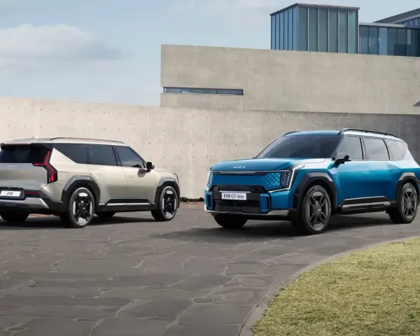 Dwa samochody elektryczne Kia EV9 w kolorach niebieskim i jasnoszarym stoją na zewnątrz.