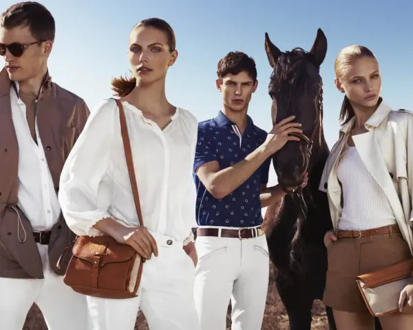 Quattro modelli con un cavallo, vestiti in stile old money, evocano un'eleganza senza tempo in un paesaggio aperto.