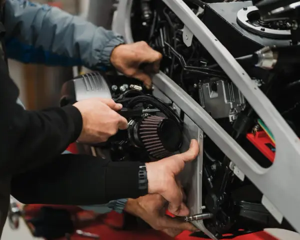 Mechanicy pracują nad motocyklem, sprawdzając filtr paliwa. Objawy jego zużycia mogą być różne.