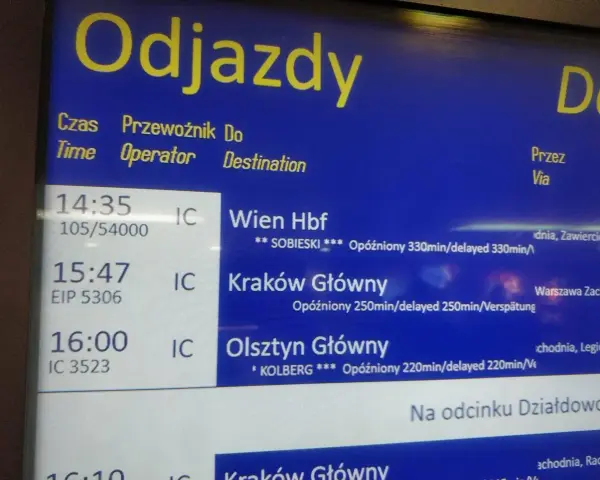 Tablica odjazdów PKP z informacjami o opóźnionych pociągach do Wiednia, Krakowa i Olsztyna.