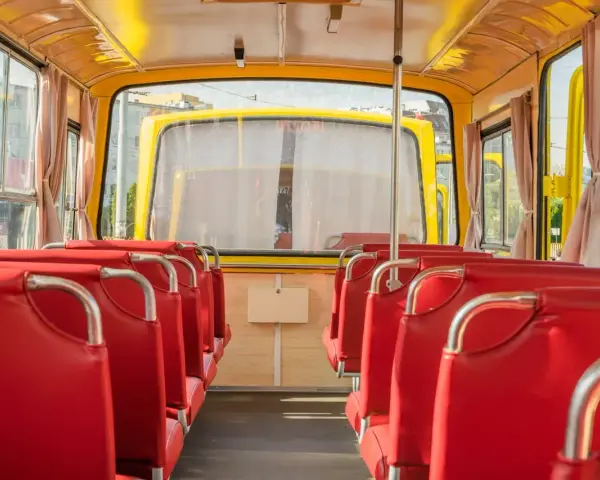 Wnętrze żółtego autobusu z czerwonymi siedzeniami, widok od tyłu.