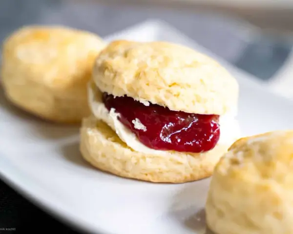 Frisch gebackene Scones mit Clotted Cream und Erdbeermarmelade, ein köstliches Rezept für den Nachmittagstee.
