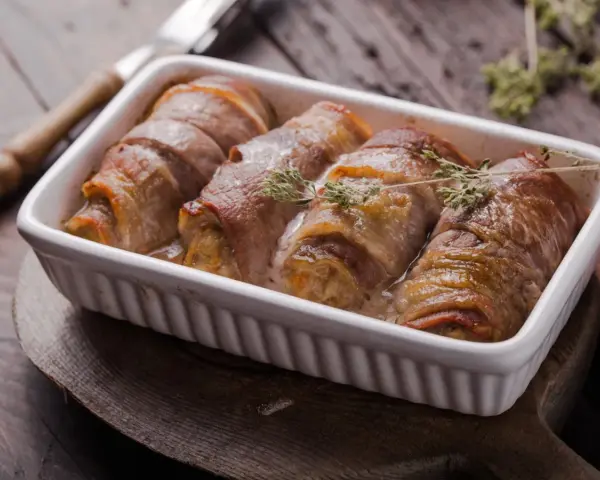 Roladki ze schabu po cygańsku, zawinięte w boczek, pieczone w sosie śmietanowym, ozdobione gałązkami tymianku.