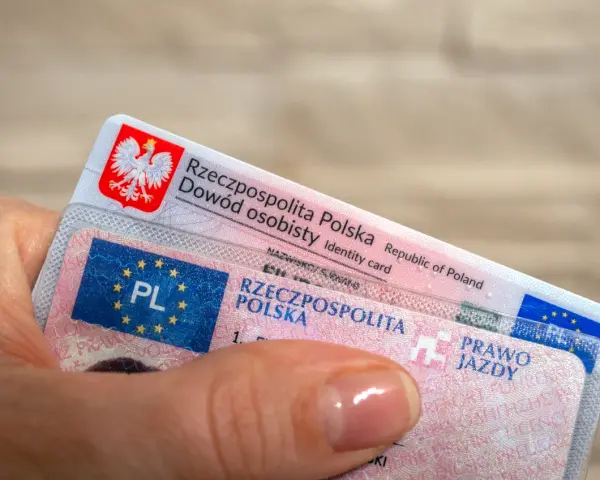 Dłoń trzyma polski dowód osobisty i prawo jazdy.