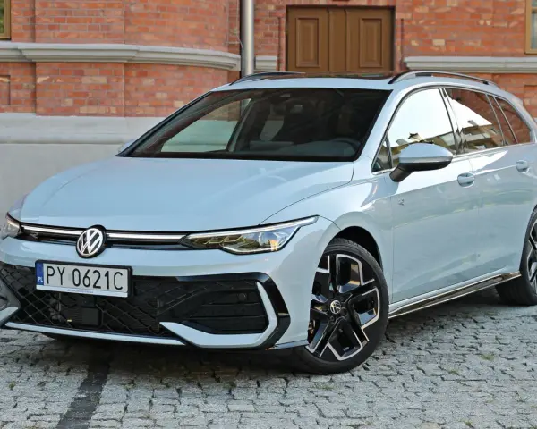 Jasny VW Golf 8 Variant na brukowanej ulicy przed ceglanym budynkiem. Elegancki kombi z nowoczesnym designem.