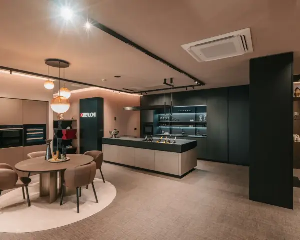 Elegante cucina scura con isola centrale e un tavolo rotondo. Il pavimento chiaro crea un contrasto moderno e luminoso.