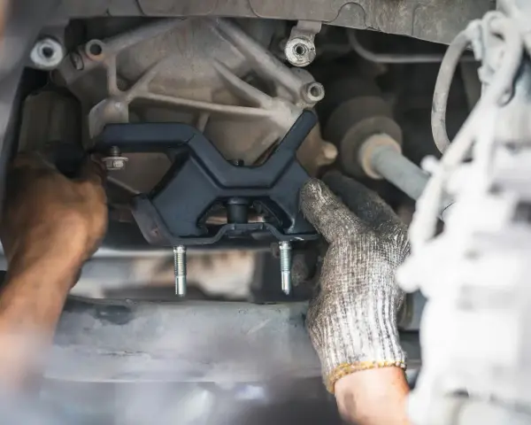 Mechanic installing a new engine mount. This repair is essential for smooth driving and can impact motor mount replacement cost.