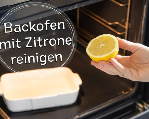 Backofen reinigen mit Zitrone: Eine Hand hält eine halbe Zitrone über eine leere Auflaufform im dunklen Backofen.