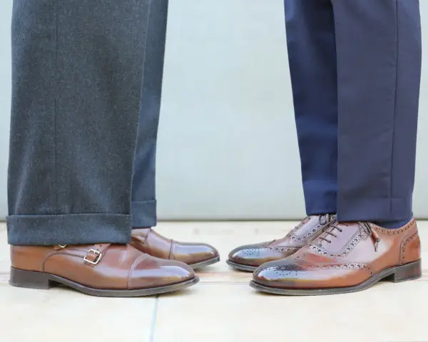Długość spodni garniturowych: jeden model ma wywinięte nogawki, drugi gładkie. Eleganckie buty męskie.