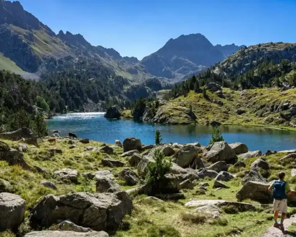 Deux randonneurs explorent un sentier rocailleux menant à un lac bleu étincelant, entouré de montagnes majestueuses. Une parfaite randonnée Val d'Aran.