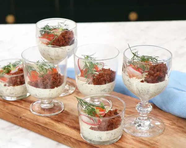Små glas med silltårta kavring, krämig sås, rom, rädisa och dill. En festlig förrätt.