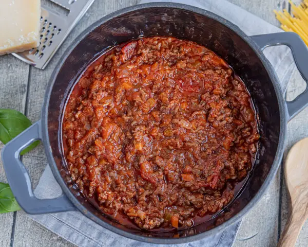 Herzhafte, beste Bolognese original im Topf, mit frischem Basilikum, Parmesan und Spaghetti daneben.