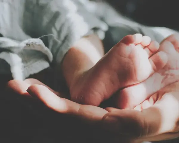 Delikatne stópki dziecka w dłoni, otulone miękkim kocykiem. Idealne dla nich jest pranie w proszku do prania dla dzieci.