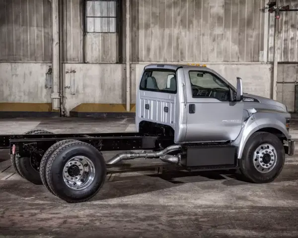 Srebrny Ford F750 bez zabudowy, gotowy do pracy. Potężna rama i podwójne tylne koła.