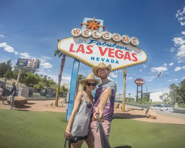 Para co przywieźć ze Stanów? Pamiątkę z Las Vegas! Uśmiechnięta para pozuje do selfie pod słynnym znakiem.