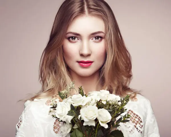 Piękna blondynka z bukietem białych róż. Jej spojrzenie sugeruje głębokie znaczenie imienia Aleksandra – obrończyni ludu.