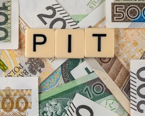 Litery "PIT" na tle polskich banknotów o różnych nominałach.