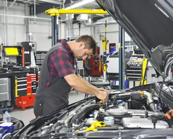 Mecánico trabajando en un motor en un taller. El sistema ERP del taller está organizado y listo para el diagnóstico.