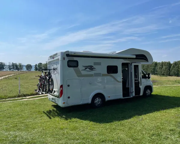Kamper na trawie, gotowy na wakacje. To ekskluzywne pole namiotowe Mazury oferuje ciszę i piękne widoki na jezioro.