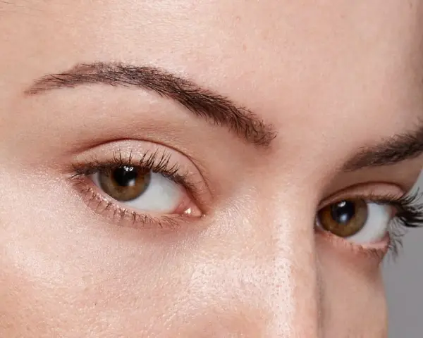 Gros plan sur des yeux aux cils longs et recourbés, encadrés par des sourcils aux forme sourcils parfaits.