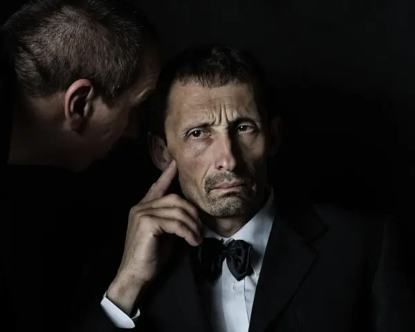 Mężczyzna w garniturze słucha szeptanych tajemnic. Czy to zasada omerty?