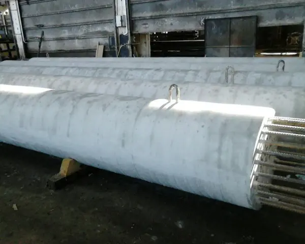 Długie, betonowe rury leżą obok siebie. Widać metalowe uchwyty do transportu. To efekt pracy z szalunkiem papierowym, który nadał im idealny kształt.