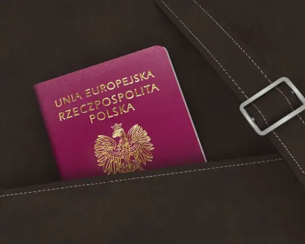 Nowy polski paszport w kolorze fuksji z godłem orła w złocie, schowany w brązowej skórzanej kieszeni.