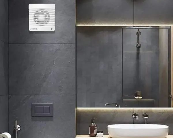 Extractor de baño blanco instalado en pared de azulejos grises.
