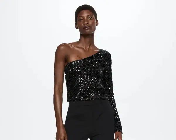 Top negro de lentejuelas asimétrico, ideal para saber como vestir para un cumpleaños de noche mujer.