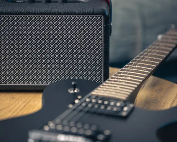 Czarna gitara elektryczna i mały wzmacniacz – to podstawa, co jest potrzebne do gitary elektrycznej, by zacząć grać.