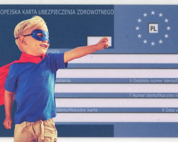 Mały superbohater z czerwoną peleryną i niebieską maską symbolizuje ubezpieczenie turystyczne dla dziecka. Europejska Karta Ubezpieczenia Zdrowotnego zapewnia bezpieczeństwo.