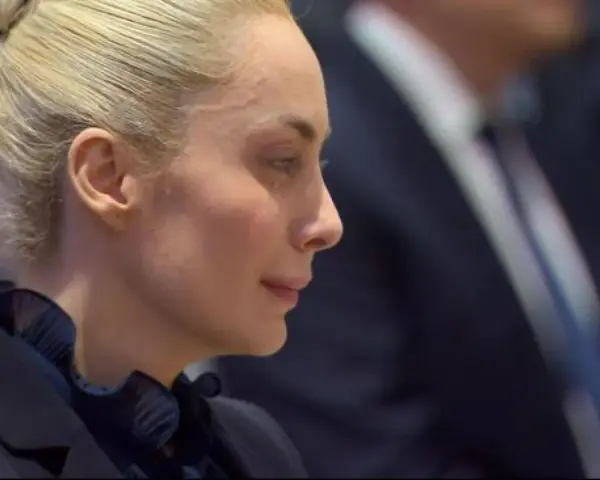 Marta Fascina, con i capelli raccolti, indossa un abito scuro. La sua espressione pensierosa suggerisce un momento di riflessione prima di un evento importante, forse legato a Silvio Berlusconi.